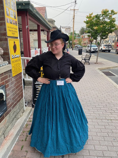 A costumed Haunted Gettysburg Tours guide standing beside the tour sign board on Steinwehr Avenue
